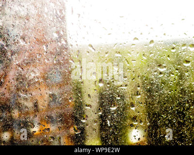 Regentropfen auf klare Glasscheibe, Reflexion des unscharfen Stadt und leichte Bokeh von Außen, schöne Farbe abstrakt, Hintergrund Stockfoto