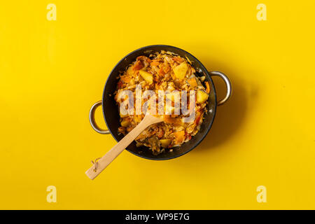Blick von oben auf die gemüseeintopf Mix im Kessel auf eine Farbe, Oberfläche mit Holzstab Stockfoto