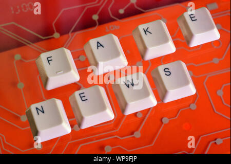 Die Tasten der Tastatur Form das Wort FAKE NACHRICHTEN auf roten Stromkreis im Hintergrund. Stockfoto