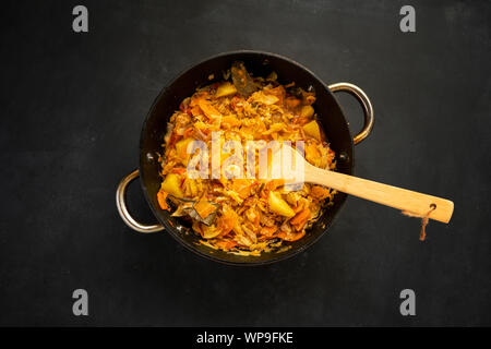 Blick von oben auf die gemüseeintopf Mix im Kessel auf eine Farbe, Oberfläche mit Holzstab Stockfoto