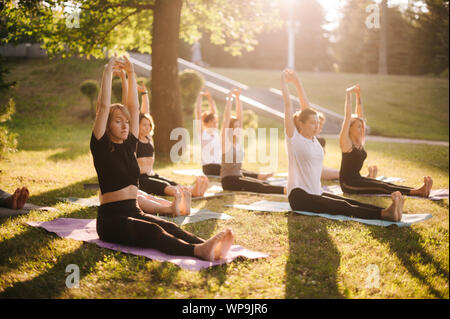 Sind eine Gruppe von Frauen Yoga und heben die Hände über den Köpfen in der Morgendämmerung Stockfoto