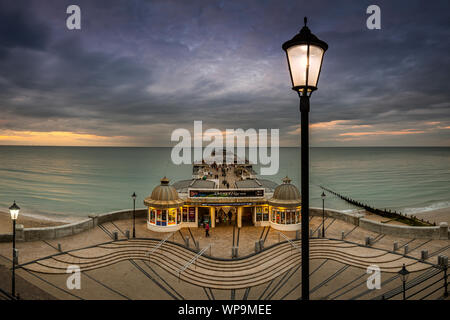 Die strassenbeleuchtung Start auf, wie die Sonne in Cromer Pier zu kommen. Stockfoto