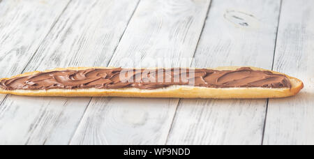 Die Hälfte der Baguette mit Schokoladencreme auf dem hölzernen Tisch Stockfoto