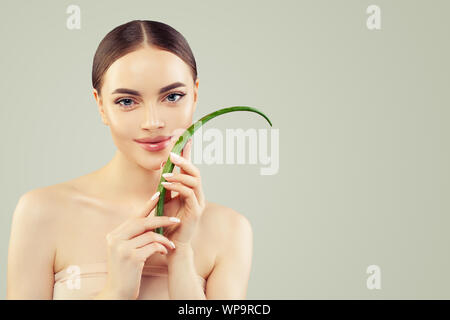 Schöne junge Frau mit klaren Haut Holding grün Aloe Vera Blatt. Hautpflege und Gesichtspflege Konzept Stockfoto