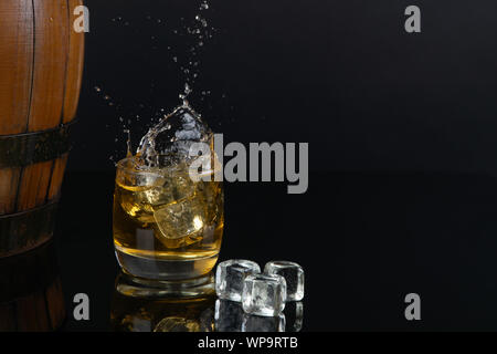 Glas Whiskey mit Splash, auf schwarzem Hintergrund Stockfoto