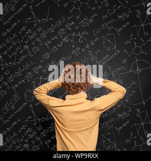 Angst Kind gegen Blackboard Hintergrund mit Wissenschaft und Mathematik Formeln Stockfoto