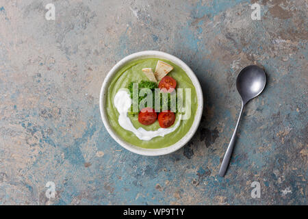 Schüssel mit broccoli Creme Suppe, Petersilie, Cherry Tomaten, Pita und Löffel auf Blau und Grün konkreten Hintergrund. Ansicht von oben, Tischplatte, flach Stockfoto