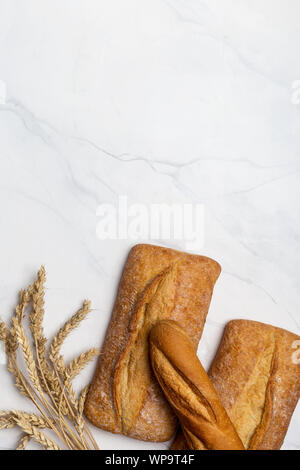 Laibe Brot mit Ähre auf weißem Hintergrund. Hintergrund für Text, Flach, Ansicht von oben Stockfoto