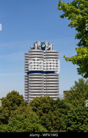 Die BMW-Turm gesehen durch Bäume, BMW Zentrale, München, Bayern, Deutschland. Stockfoto