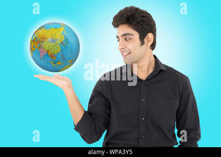 Geschäftsmann zeigt einen Globus und lächelt Stockfoto