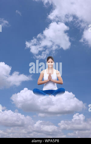 Junge Frau, die auf Wolken sitzt und Yoga praktiziert Stockfoto