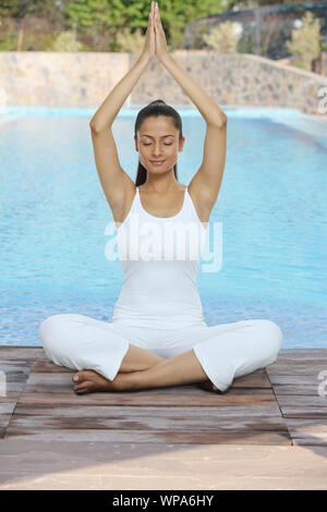 Junge Frau, die am Pool Yoga praktiziert Stockfoto