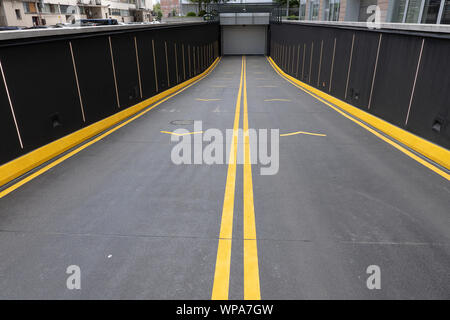 Eingang von der Straße zu einer Tiefgarage in der Stadt, laballed mit leuchtend gelben Farbe. Stockfoto