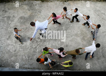 (190908) - GUIYANG, Sept. 8, 2019 (Xinhua) - Jiang Tongying spielt mit Kindern bei Hua'ao Grundschule in Jianhe Bezirk Qiandongnan Miao und Dong Autonomen Präfektur, Südwesten Chinas Provinz Guizhou, Sept. 5, 2019. Jiang Tongying ist eine 56-jährige Lehrerin von Dong ethnische Gruppe in Hua'ao Primary School, wo er seit 1982 tätig ist. Obwohl einige junge Lehrer verband ihn zu lehren, sie verließ schließlich wegen der harten Lebensbedingungen oder unbequem Transport. Ab 2013 wird die Schule sah weniger und weniger Anzahl der Schüler wie die Einheimischen gingen als Wanderarbeitnehmer oder reloc Stockfoto