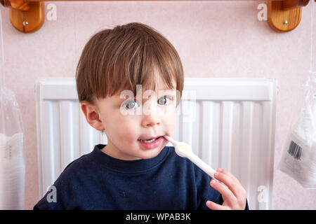 Kaukasier Kind, Junge, 3-4 Jahre alt. Kopf und Schultern, Boy's Holding kind Zahnbürste und putzen Sie die Zähne beim Betrachter. Große Augen. Stockfoto