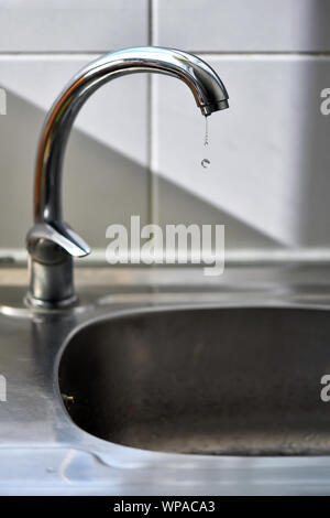 Sauberes Wasser fallenden Tropfen aus einen tropfenden Wasserhahn Küche, eine unnötige Verschwendung von Wasser in einer Welt, die von Wasserknappheit bedroht. Stockfoto