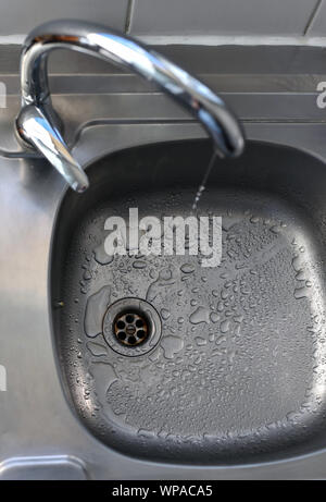 Sauberes Wasser fallenden Tropfen aus einen tropfenden Wasserhahn Küche, eine unnötige Verschwendung von Wasser in einer Welt, die von Wasserknappheit bedroht. Stockfoto