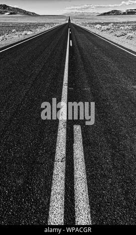 Blick auf eine endlose gerade Straße durch die Wüste in den USA läuft Stockfoto