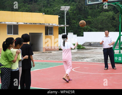 (190908) -- TIANDONG, Sept. 8, 2019 (Xinhua) - Wei Guoji spielt Basketball mit Studierenden an Tuogua Grundschule an Tuogua Dorf in Zuodeng Yao ethnischen Gemeinde Tiandong County, South China Guangxi Zhuang autonomen Region, Sept. 3, 2019. In den abgelegenen Bergen County, Tiandong Tuogua Grundschule ist über 60 km entfernt von der Kreisstadt, die nur noch mit einem robusten Mountain Road führen kann. Die 53-jährige Wei Guoji, ein Eingeborener ins Dorf, ist das Prinzip der Dorfschule. Wei wurde als Ersatz Lehrer der Schule rekrutiert nach Abschluss der Junior High School an Stockfoto