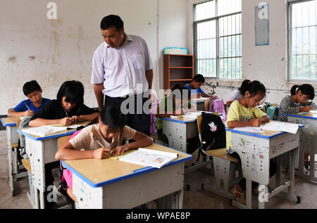 (190908) -- TIANDONG, Sept. 8, 2019 (Xinhua) - Wei Guoji Tutoren Schüler in Heimarbeit an Tuogua Grundschule an Tuogua Dorf in Zuodeng Yao ethnischen Gemeinde Tiandong County, South China Guangxi Zhuang autonomen Region, Sept. 3, 2019. In den abgelegenen Bergen County, Tiandong Tuogua Grundschule ist über 60 km entfernt von der Kreisstadt, die nur noch mit einem robusten Mountain Road führen kann. Die 53-jährige Wei Guoji, ein Eingeborener ins Dorf, ist das Prinzip der Dorfschule. Wei wurde als Ersatz Lehrer der Schule rekrutiert nach Abschluss der Junior High School an der Stockfoto