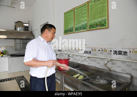 (190908) -- TIANDONG, Sept. 8, 2019 (Xinhua) - Wei Guoji hilft Gemüse putzen in der Küche der Grundschule an Tuogua Tuogua Dorf in Zuodeng Yao ethnischen Gemeinde Tiandong County, South China Guangxi Zhuang autonomen Region, Sept. 3, 2019. In den abgelegenen Bergen County, Tiandong Tuogua Grundschule ist über 60 km entfernt von der Kreisstadt, die nur noch mit einem robusten Mountain Road führen kann. Die 53-jährige Wei Guoji, ein Eingeborener ins Dorf, ist das Prinzip der Dorfschule. Wei wurde als Ersatz Lehrer der Schule nach Abschluss der Junior High eingestellt Stockfoto