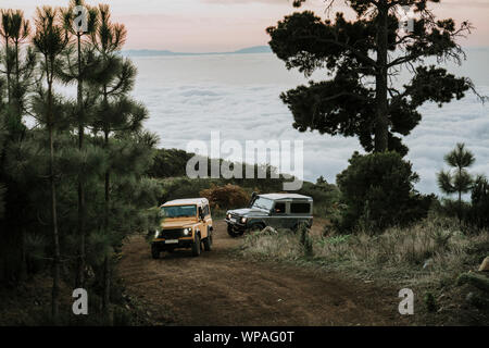 Freunde fahren zwei 4x4 beim Sonnenuntergang über den Wolken Stockfoto