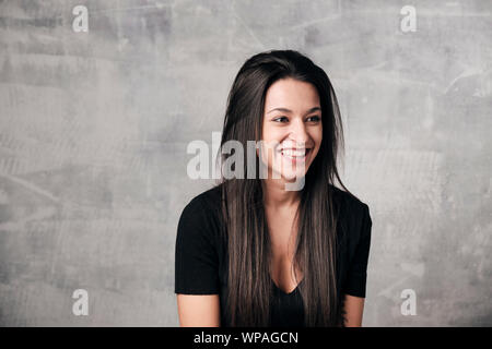 Portrait von fröhliche junge Frau in Zement Hintergrund lachen Stockfoto
