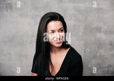 Portrait von fröhliche junge Frau in Zement Hintergrund isoliert lächelnd Stockfoto