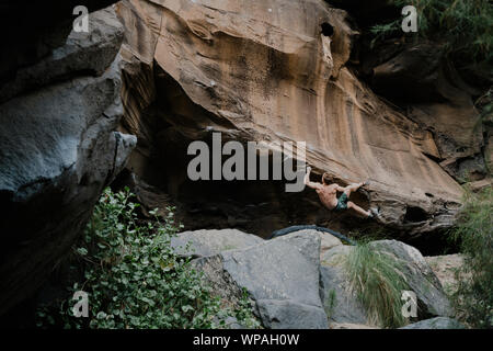 Man Klettern ein Boulder mit einigen Wellen Texturen Stockfoto