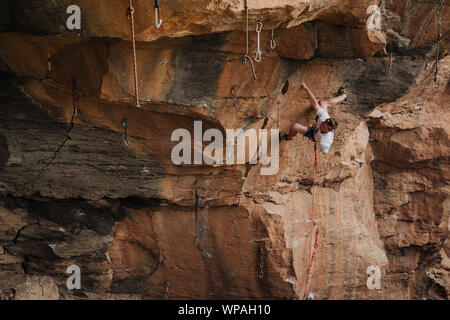 Ein junger Mann Kletterer führen Klettern in einem überhängenden Route Stockfoto