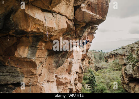 Ein junger Mann Kletterer führen Klettern in einem überhängenden Route Stockfoto