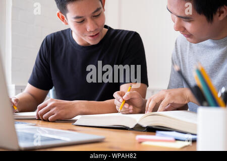 Lernen, Bildung und Schule Konzept. Junge Männer Studieren für einen Test oder eine Prüfung. Tutor Bücher mit Freunden. Junge Studenten Campus hilft Freund Griffplatte in Stockfoto