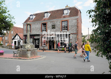 Geschäfte, Touristen mit Rucksäcken, die nach draußen gehen und Blick auf die Hauptstraße in Alfriston Village in East Sussex, England, Großbritannien KATHY DEWITT Stockfoto