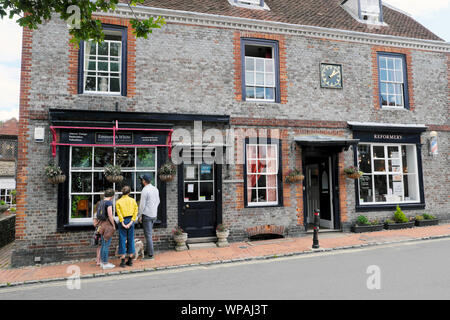 Familie, die im Schaufenster Geschäfte in einem denkmalgeschützten Gebäude an der Hauptstraße von Alfriston Village in East Sussex, England, anschauen, KATHY DEWITT Stockfoto