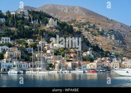 Insel Symi, Griechenland, Europa, August 2019. Blick auf das Dorf Zentrum mit dem Hafen und den farbigen Gebäude und Häuser Stockfoto