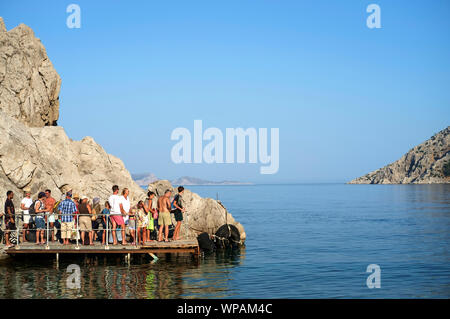 Insel Symi, Griechenland, August 2019. Gruppe von Touristen am Pier warten auf die Taxi-Fähre Stockfoto