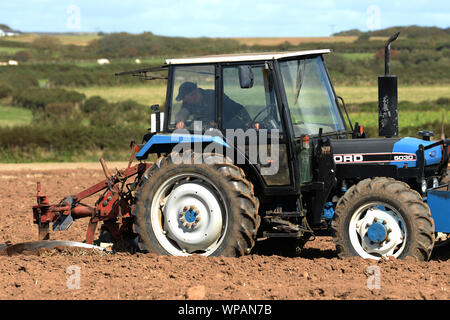 Landwirt sorgfältig Uhren seinem Pflug aus der Kabine des Traktors die Breite, Tiefe und Einheitlichkeit der jedes Grundstück der Ackerfurchen Gower Pflügen steuern Stockfoto