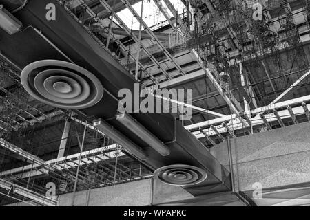 BW Ton, Low Angle Innenansicht der offenen Decke der alten Fabrik aufgeben oder industrielle Gebäude, AC verhalten System und hängenden Ketten zeigen. Stockfoto