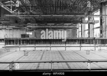 Schwarze und weiße Ton, Innenansicht der offenen Zimmer in alten Verlassen der Fabrik oder Industriegebäude mit horizontalen Reihe hängenden Ketten. Stockfoto