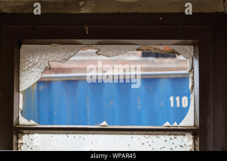 Close up Innenansicht der Scherben auf alten Holz- Fenster der industriellen Gebäude- und Hintergrund der äußeren blauer Container. Stockfoto