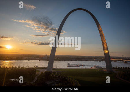Barge Traffic auf dem Mississippi River Pass den Gateway Arch National Monument bei Sonnenuntergang August 29, 2019 in St. Louis, Missouri, USA. Eine typische Barke trägt 1500 Tonnen Fracht, die 15 Mal größer ist als der Schienenbus und 60 Mal höher als bei einem Lkw-anhänger. Eine durchschnittliche Fluss schleppen auf dem Mississippi Fluss ist 15 Lastkähne, bestehend aus 5 Kähne zusammen gebunden und 3 nebeneinander. Die gleiche Last würde einen Zug 3 Meilen lange oder Linie der Nutzfahrzeuge ausdehnen mehr als 35 Meilen. Stockfoto