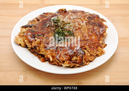 Okonomiyaki japanische Pfannkuchen essen auf dem Teller auf dem Tisch isoliert Stockfoto