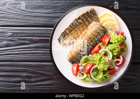 Gesundes Essen gegrillte Makrelen Filet mit Zitrone und frischen Salat close-up auf einem Teller auf den Tisch. Horizontal oben Ansicht von oben Stockfoto