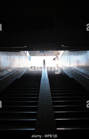 MATSUYAMA, Japan - 13 Aug, 2019: Eine vertikale Schuß einer Person die Treppen mit Geländer auf eine Mauer aus Stein Stockfoto