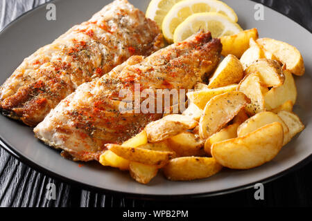 Portion gegrillte Makrelen Filet mit Kartoffelecken und Zitrone closeup auf einem Teller auf den Tisch. Horizontale Stockfoto