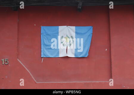 Flagge Guatemala gegen die Rote Wand in Antigua. Stockfoto