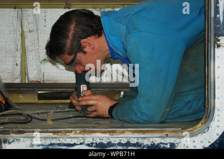 Greymouth, Neuseeland, ca. 2006: Ein Ingenieur schleift aus Nieten in den Boden eines Dornier 228 Flugzeugen Stockfoto