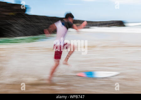 Junger Mann laufen und springen auf einem skim Board im flachen Wasser am Strand auf Maui, Hawaii, USA Stockfoto