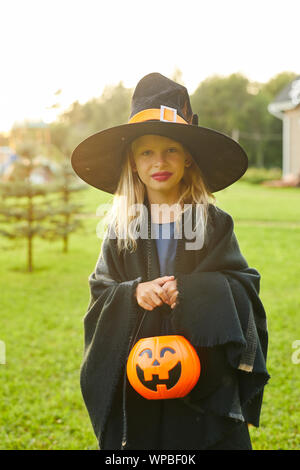 Taille bis Portrait von cute Teenager verkleidet als Hexe posiert im Freien auf Halloween und Holding Trick oder Festlichkeit Korb, kopieren Raum Stockfoto