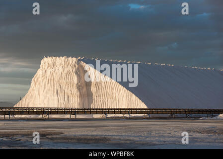 Berg der Frisch produzierte Salz in offene Fläche Kochsalzlösung mit Förderband bei Sonnenuntergang Stockfoto